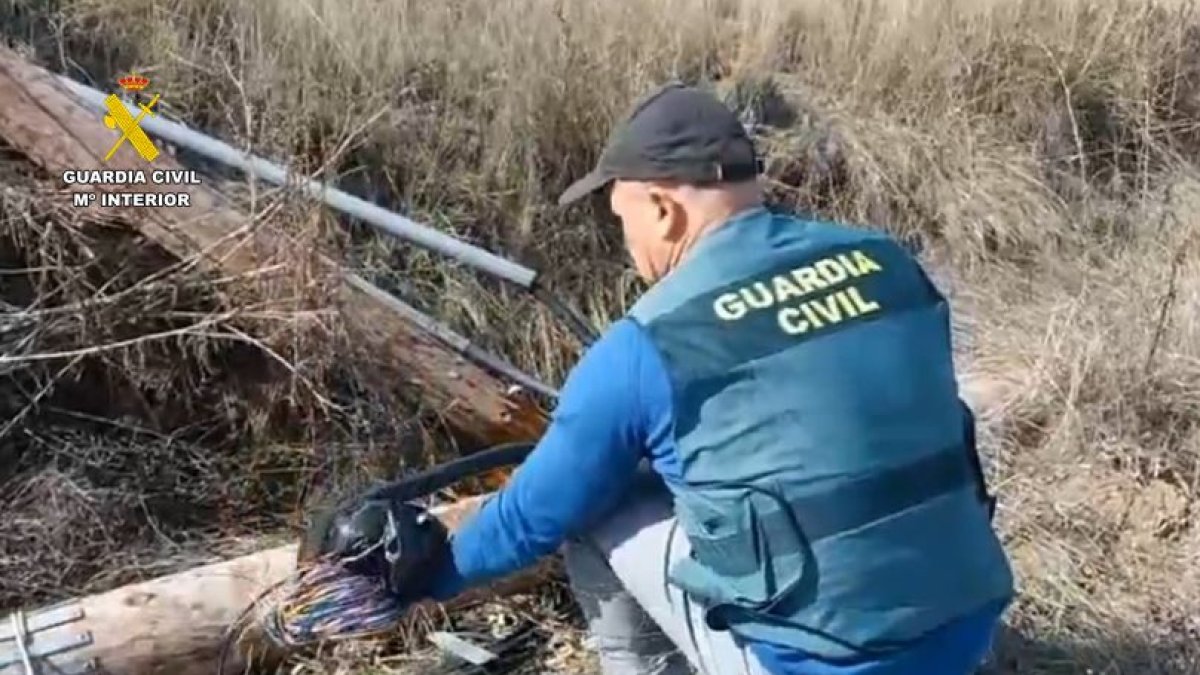 Un agente de la Guardia Civil inspecciona el cableado dañado tras el robo.
