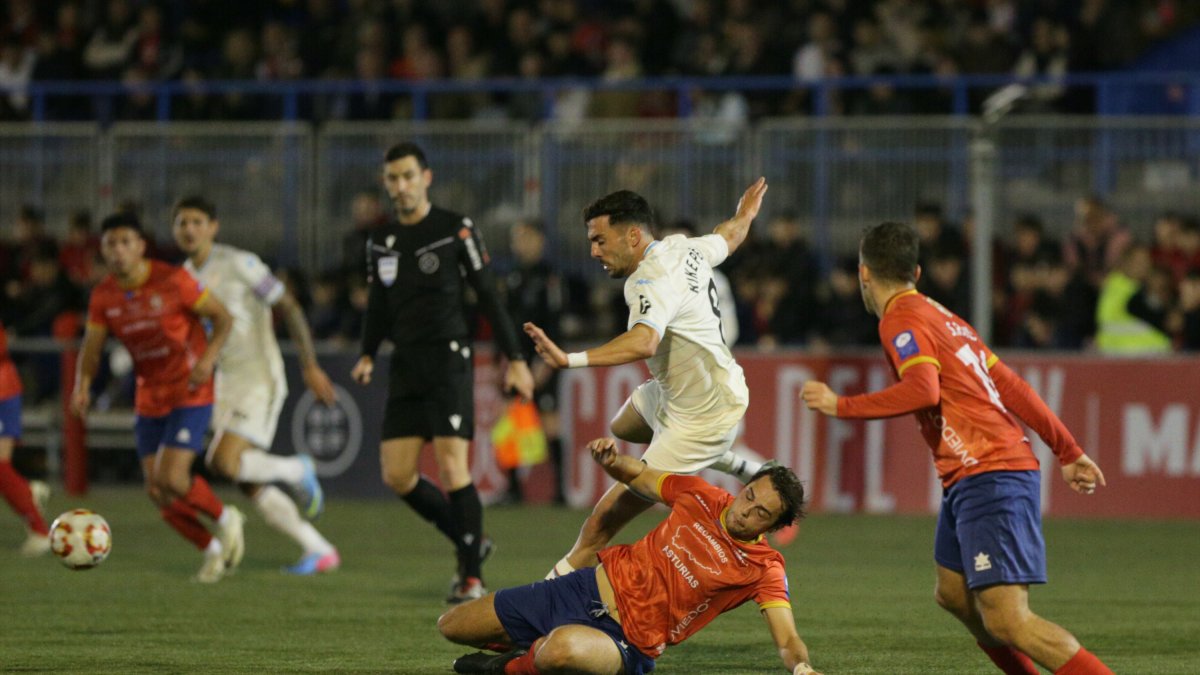 Kike intenta avanzar ante un jugador del Astur que busca obstaculizarlo.