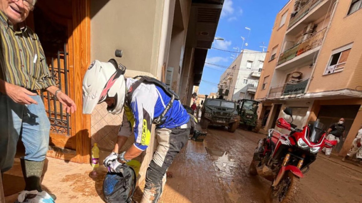 Un motero entrega productos básicos a un afectado por la DANA en Valencia