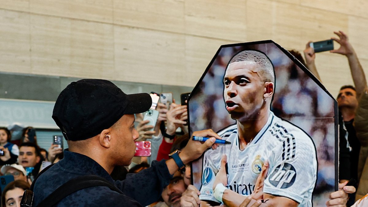 Mbappe firma un poster suyo de un joven aficionado a su llegada al aeropuerto de Villanubla.