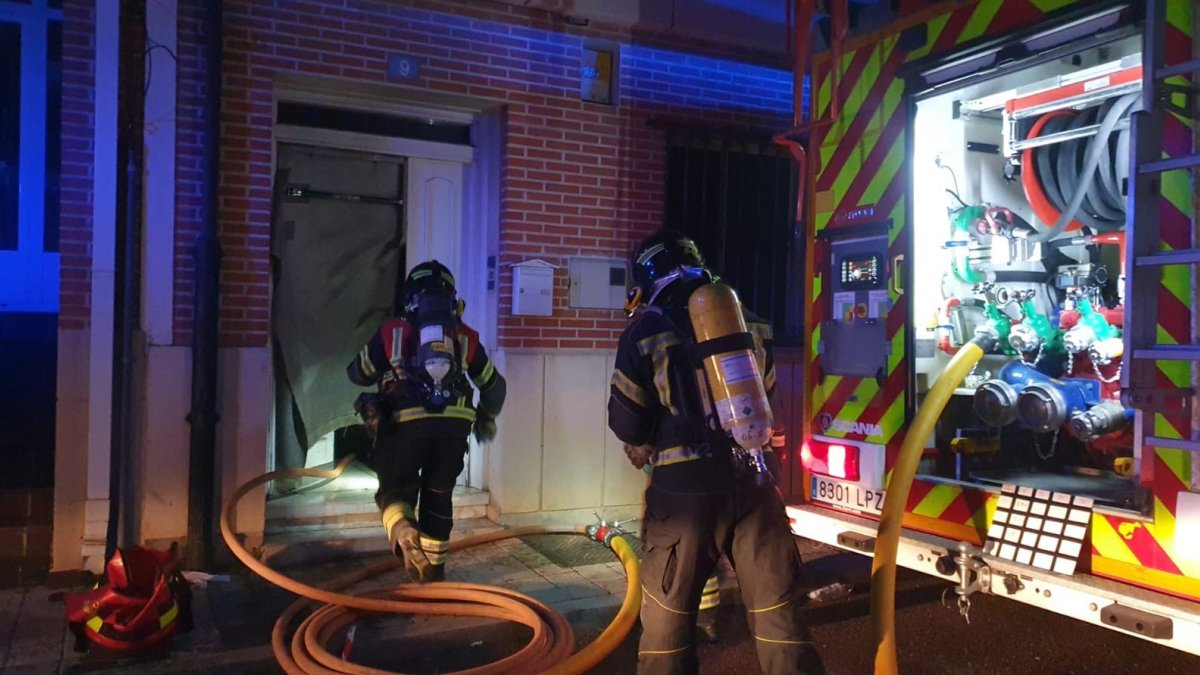 Bomberos de la Diputación acceden a la vivienda donde se produjo el incendio de un coche en el garaje.