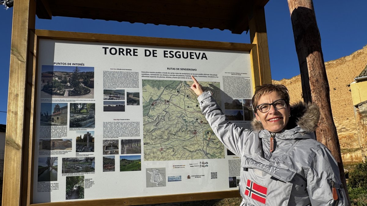 Inma Gómez señala el panel informativo de las rutas de senderismo habilitadas en Torre de Esgueva.