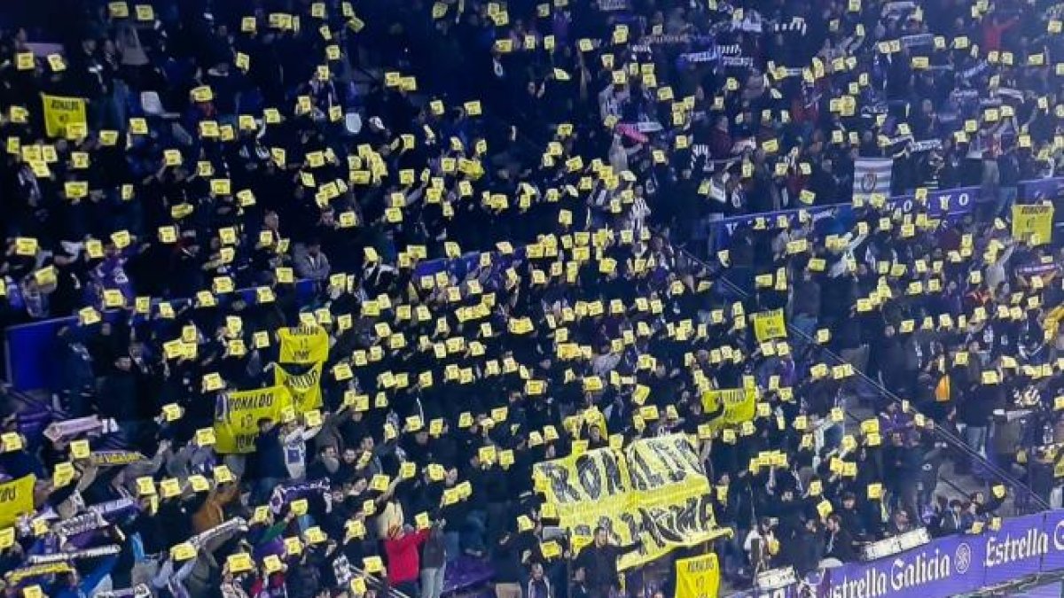 Aficionados blanquivioleta sostienen pancartas amarillas de 'Ronakdo go home' en un partido.