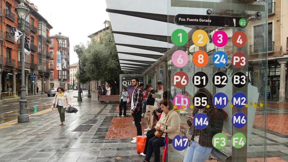 Varias personas miran el móvil mientras esperan al autobús, en una de las paradas de la línea 1.