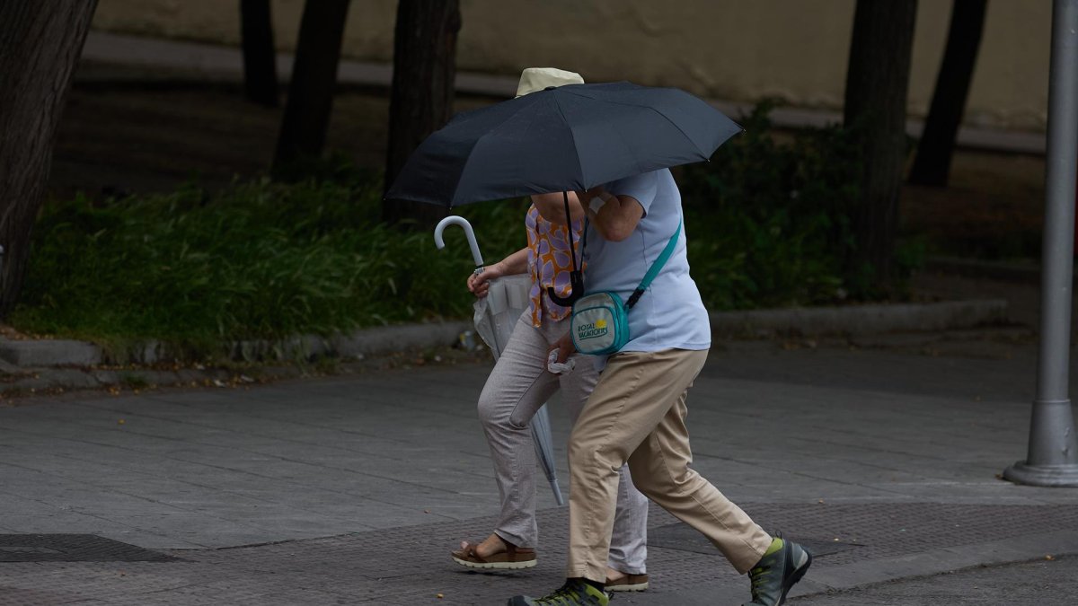 Imagen de archivo de dos personas se protegen de la lluvia con un paraguas