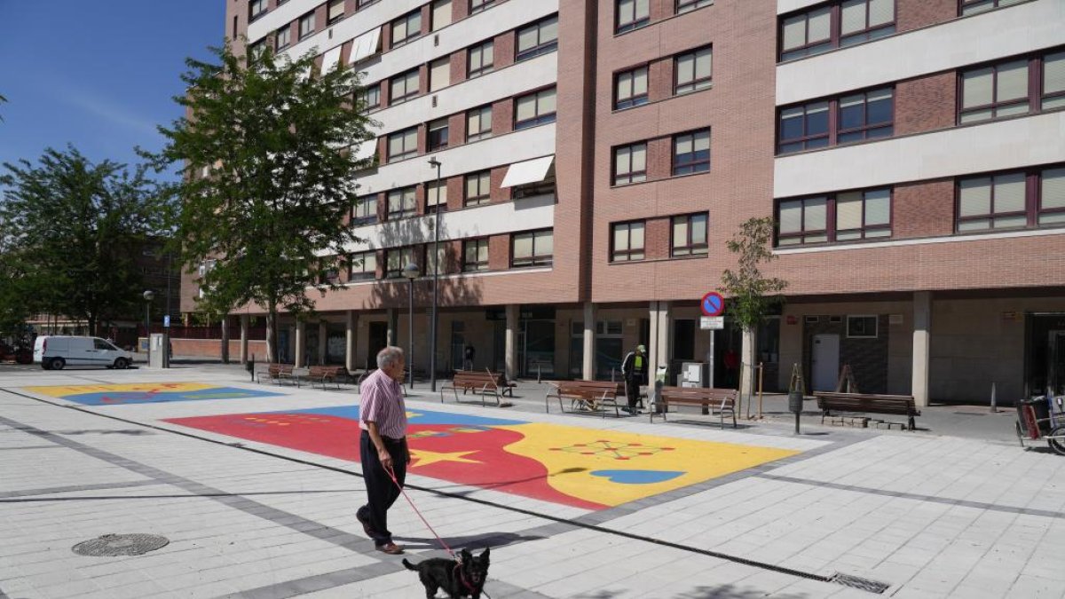 Un hombre con su perro pasea por la nueva plaza de la India en Valladolid.
