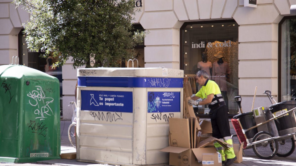 Un operario recoge cartones en un contenedor del centro de Valladolid.