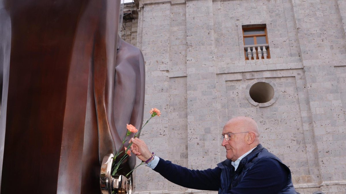 El alcalde de Valladolid, Jesús Julio Carnero, pone flores en la plaza de Portugalete en la escultura en homenaje a las víctimas de accidentes de tráfico.