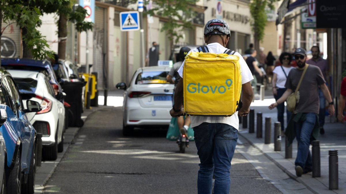 Dos usuarios de patinete eléctrico circulan por  una calzada.