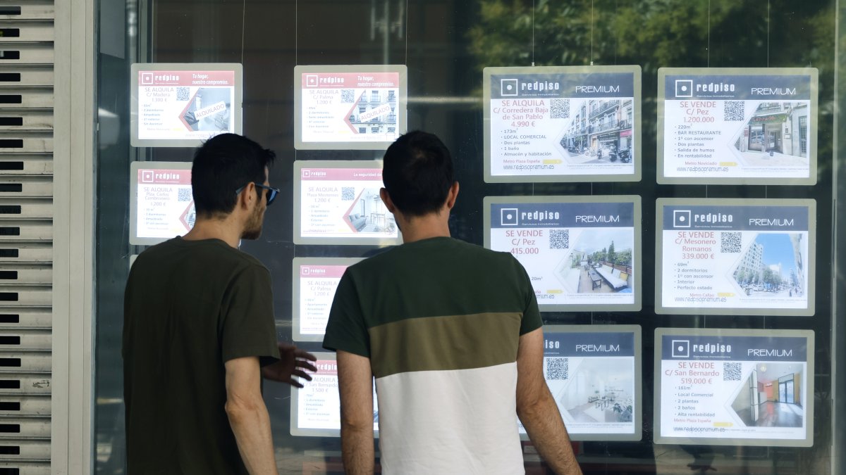 Dos jóvenes en el escaparate de una inmobiliaria