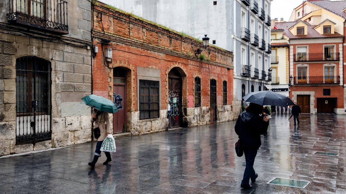 Varios viandantes se protegen de la lluvia en el centro de Valladolid