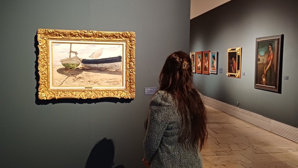 Una mujer contempla el óleo de 1900 ‘Barcas en la playa’, de Joaquín Sorolla.
