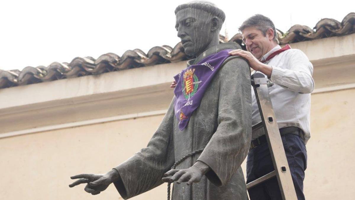 Un operario coloca el pañuelo festivo a la estatua de San Pedro Regalado en Valladolid, símbolo de la celebración de su festividad cada 13 de mayo