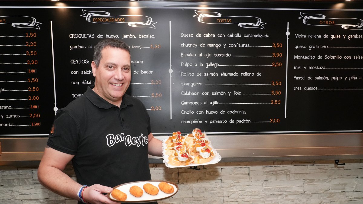 Alejandro Burgos muestra un plato con croquetas de huevo cocido y una bandeja con varias tapas de queso de cabra, mermelada  y cebolla caramelizada.