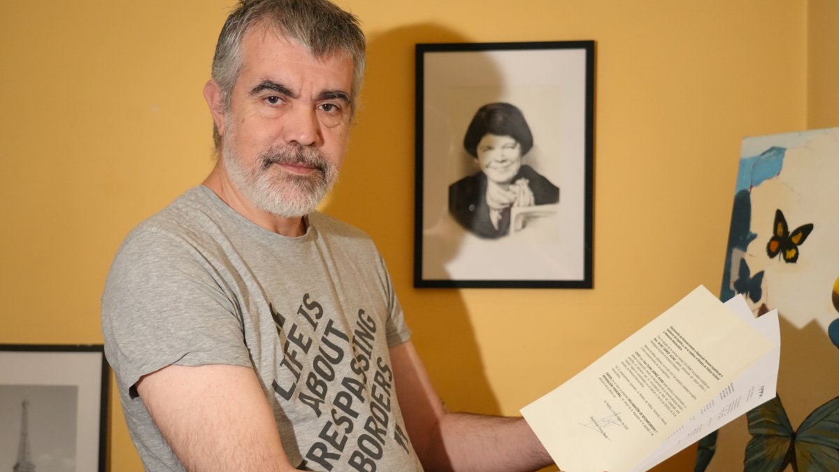 Olmo Gómez con los papeles que le reconocen como 'bebe robado' y detrás una caricatura de su madre biológica