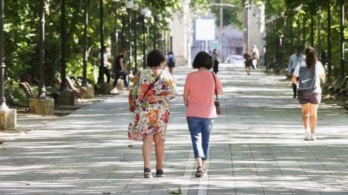 Dos mujeres se protegen del calor en el Campo Grande de Valladolid.