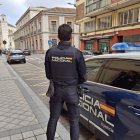 Agente del Cuerpo Nacional de Policía de Valladolid junto a un coche patruila.