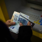 Una mujer saca dinero de un cajero automático.-EMILIO MORENATTI / AP