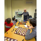 El profesor Fernando les enseña algunas jugadas para que den jaque mate en una partida, mientras algunos de los chavales apuntan las técnicas en un cuaderno.-MIGUEL ÁNGEL SANTOS