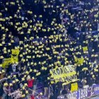 Aficionados blanquivioleta sostienen pancartas amarillas de 'Ronakdo go home' en un partido.