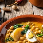 El potaje de vigilia, con garbanzos, espinacas y bacalao, es uno de los guisos más tradicionales de la Cuaresma, servido aquí con huevo cocido en plato de barro