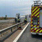 Los Bomberos de la Diputación de Valladolid, en el lugar del accidente con el camión volcado al fondo.