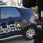 Agente y coche patrulla de la Policía Nacional.