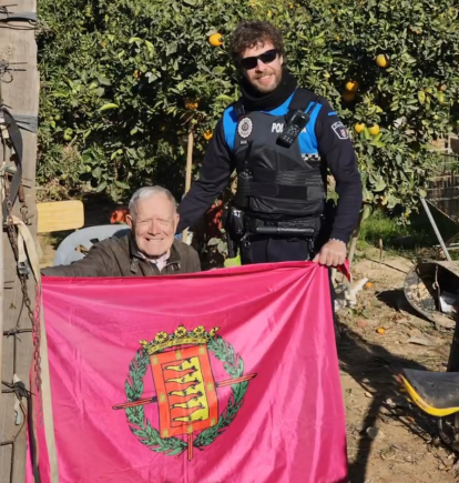 Uno de los agentes desplazados en Sedaví con un vecino de la localidad y la bandera vallisoletana.