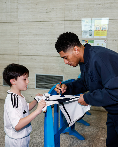 Bellingham firma un autógrafo a un joven aficionado vallisoletano del Real Madrid a su llegada al aeropuerto.