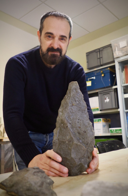 Fernando Diez posa con una reproducción de un gran bifaz hallado en FLK West.