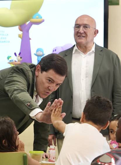 Mañueco choca la mano de los uno de los niños del programa Pajarillos Educa ante la presencia de Carnero.