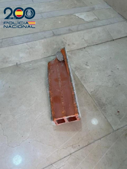 Ladrillo con el que se ha roto el cristal de la puerta del edificio.