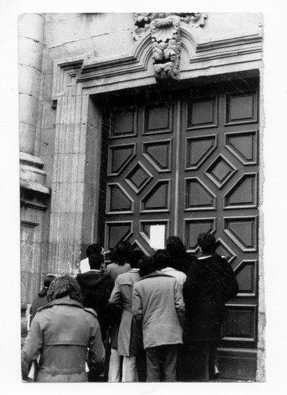 Un grupo de estudiantes observa un papel colocado en la puerta cerrada de la fachada principal de la Universidad en 1975